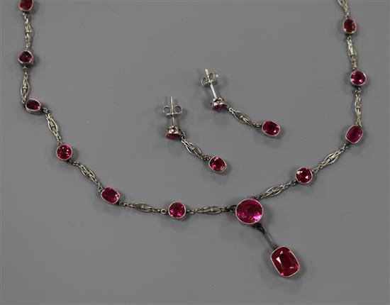 A suite of white metal and synthetic ruby set jewellery comprising a spectacle set drop pendant necklace and a pair of earrings,